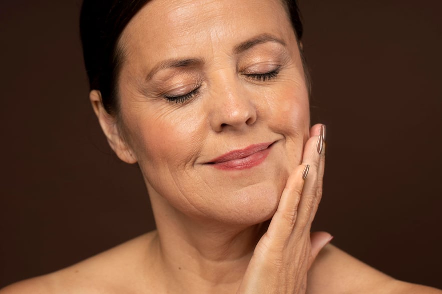 Middle-aged woman gently touching her smooth face with closed eyes